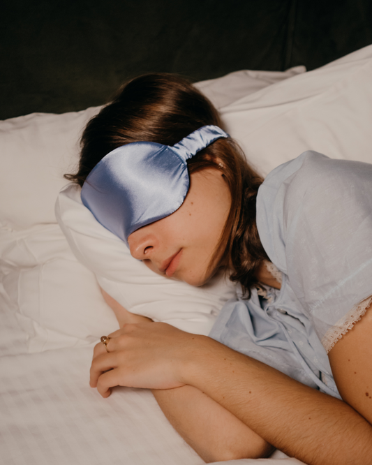Frau mit Schlafmaske schläft entspannt im Bett